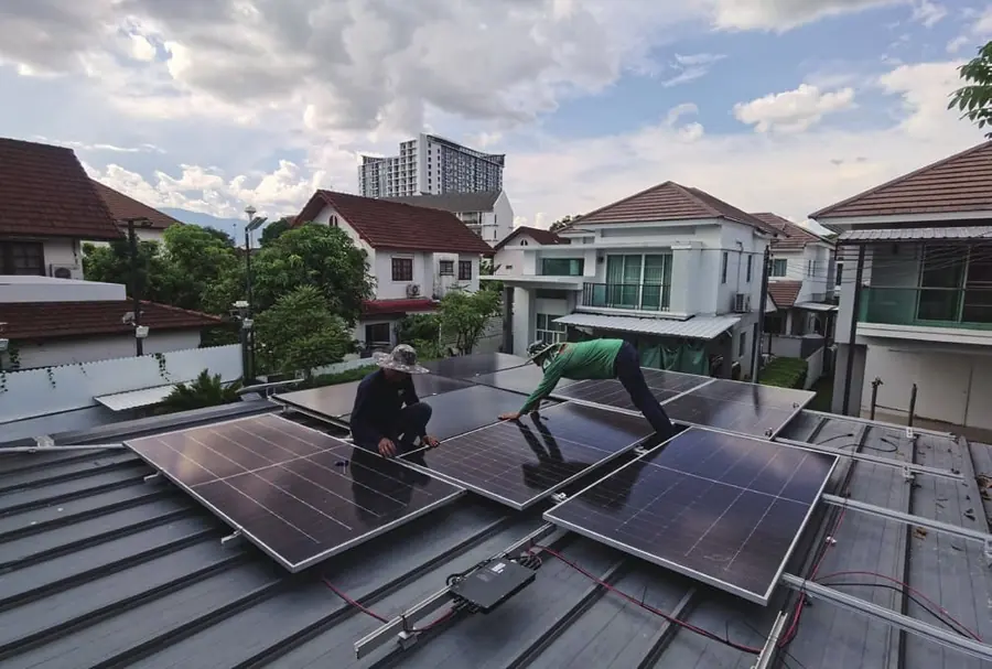 Installateurs posant des modules sur un toit en tuiles